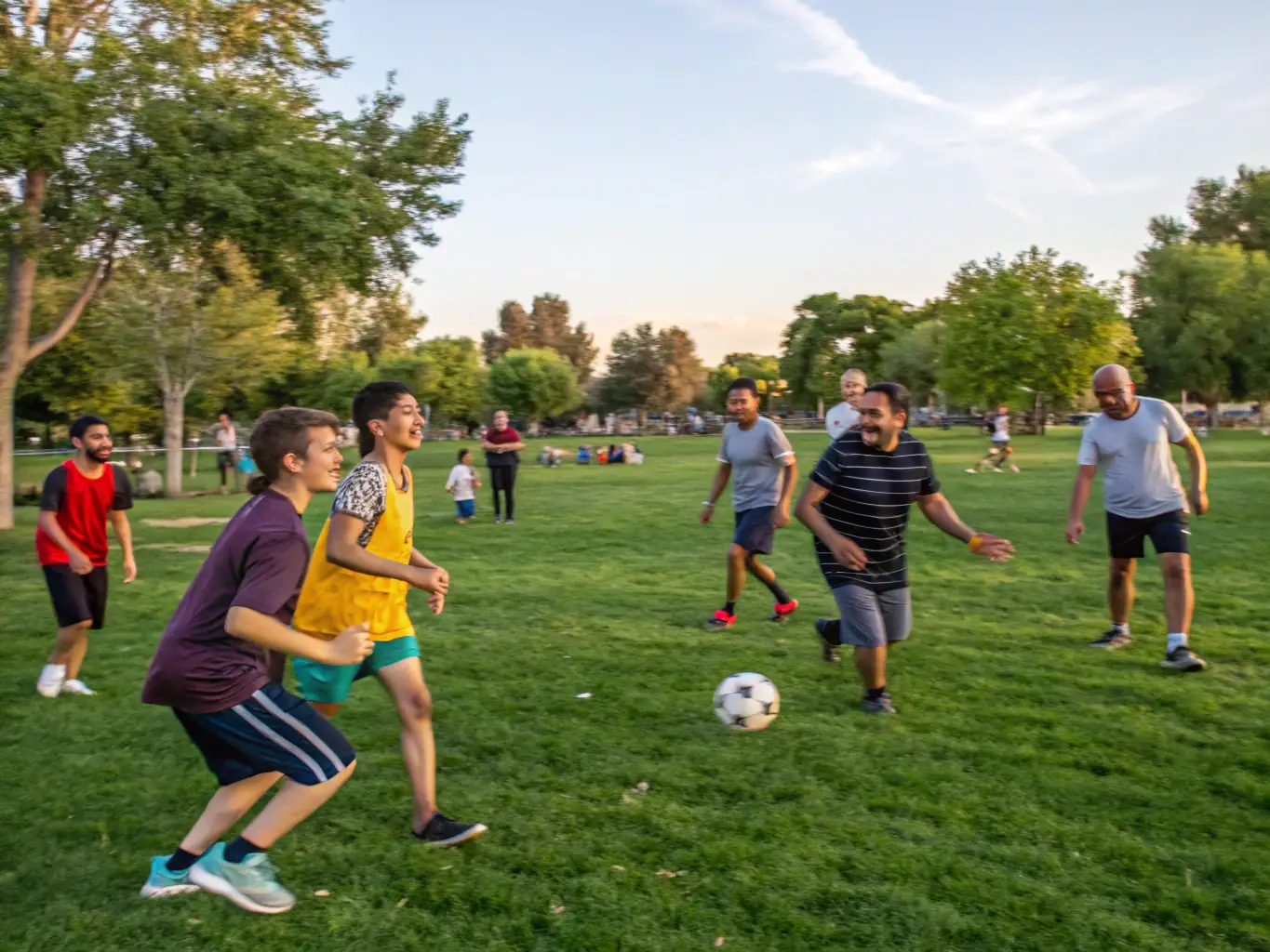 A group of diverse individuals participating in a friendly soccer match in a local park, showcasing teamwork and community spirit.